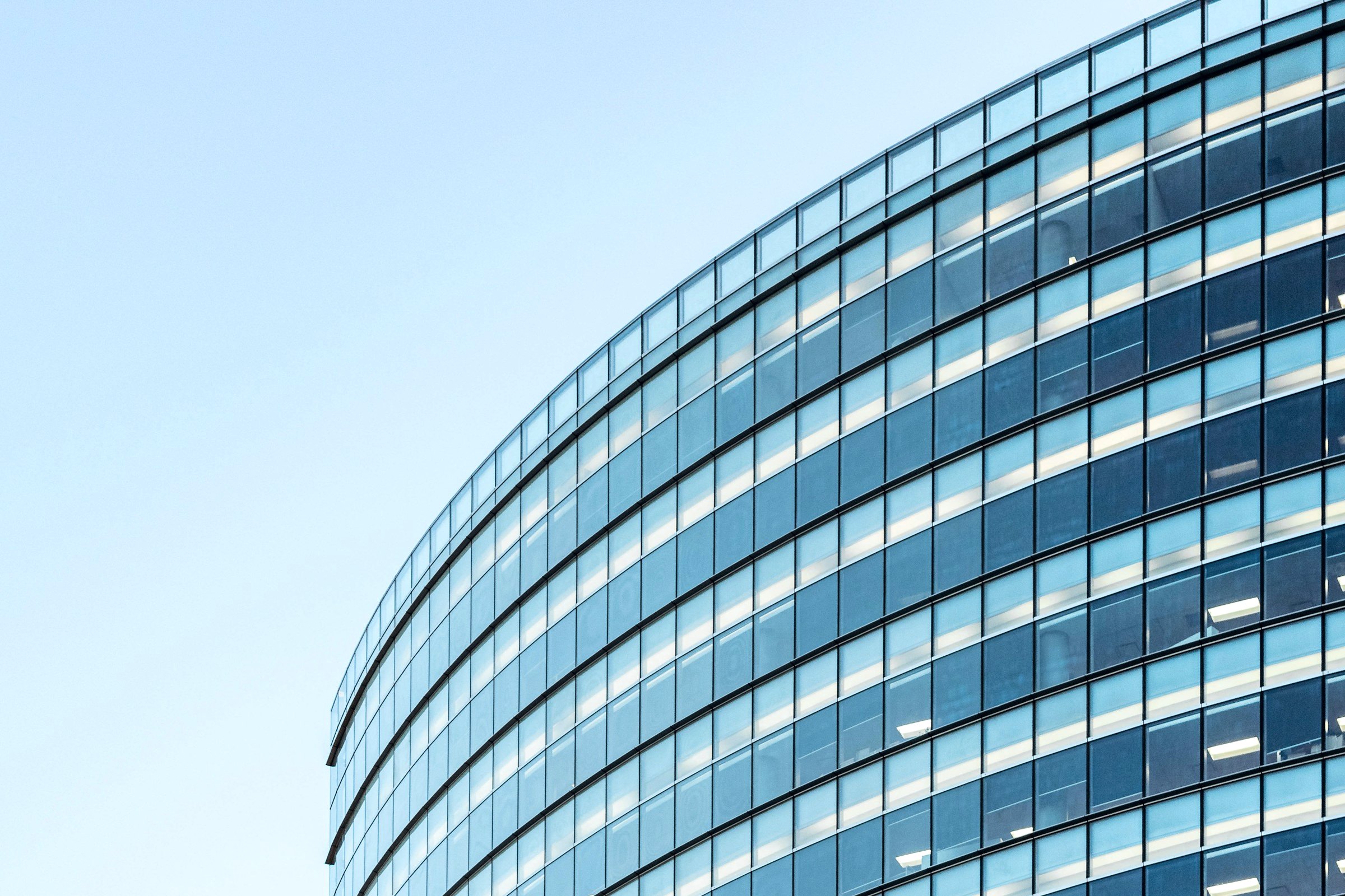 Curved glass office building against a pale sky
